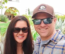 Kyle and Angela, a military realtor and veteran real estate agent couple behind PCS JOES, smiling in front of a Southern California home.